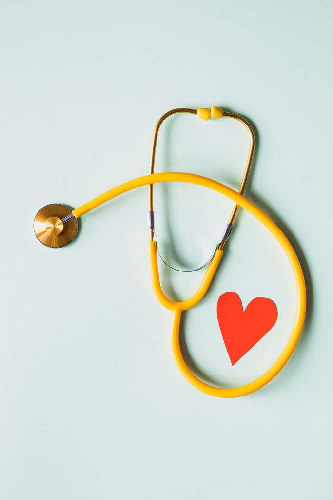 Paper red heart placed on white background with yellow medical stethoscope for heart care